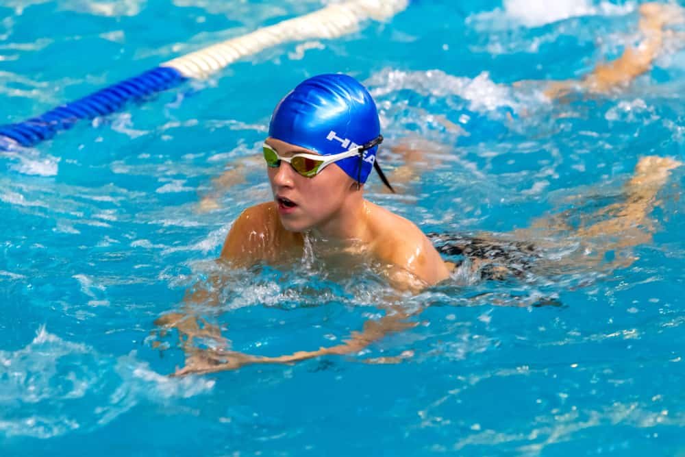 Children, athletes, swimmers swim along tracks in sports pool for swimming